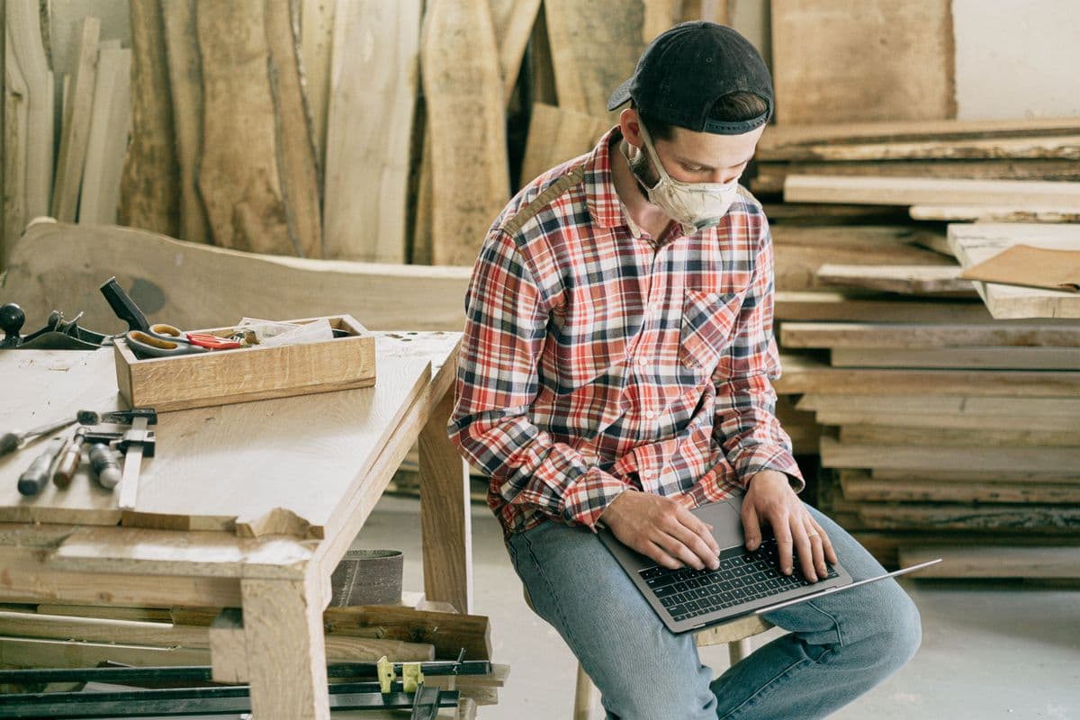 A tradesperson working on a laptop in a workshop, representing a small business owner weighing up a website builder